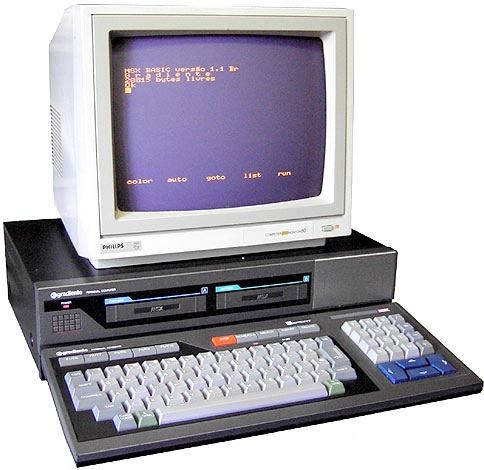 Um microcomputador clone brasileiro dos anos 80, da marca Gradiente, com monitor, teclado e dois drives de disquete.